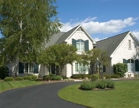 Beautiful white two story brick home. Very colorful photo with blue sky and green grass. Typical new home in the suburbs of the United States. Just one of many home or house photos in my gallery.